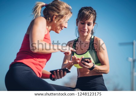 Two women consult mobile phone during training.