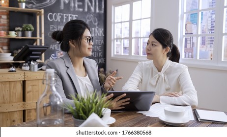 two women consultants doing business conference in meeting cafe store. young office lady in suit asking colleague advice in coffee shop. asian korean female colleagues discussing on digital tablet. - Powered by Shutterstock