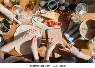 Two Women Cooking Pizza At Home. Filling Pizza With Ingredients. Top View. Overhead View.