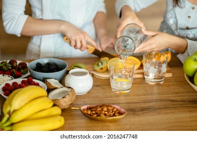 Two Women Cooking Together, Close Up Of Hands Pouring Cold Water To The Glass.