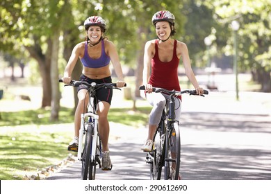 Two Women Cycling Through Park