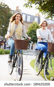 Two Women Cycling Through Urban Park Together