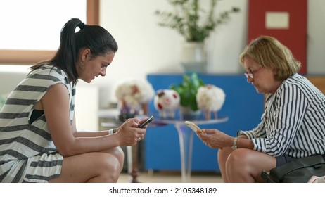 Two Women From Different Generations Looking At Smartphone Devices Separately