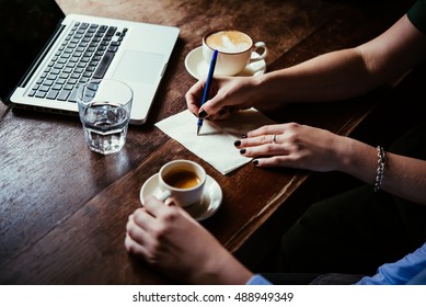 Two women discussing business projects in a cafe while having coffee. Startup, ideas and brain storm concept