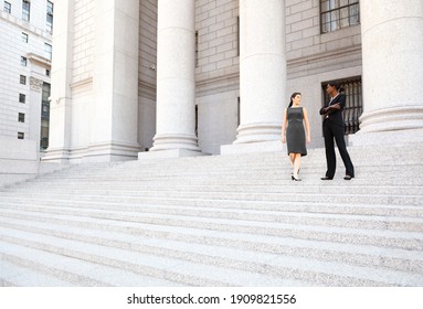 Two women in discussion on the exterior steps of a courthouse. Could be lawyers, business people etc.