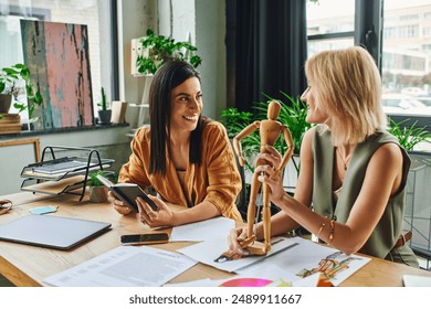 Two women, dressed in smart casual attire, collaborate on a project in a modern workspace. - Powered by Shutterstock