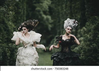 Two women dresses like heroes from 'Alice in Wonderland' pose in a green park