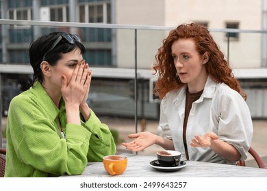 Two Women Engaged in Intense Conversation Over Coffee at Outdoor Café in Urban Setting - Powered by Shutterstock