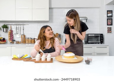 Two women enjoy in a fun cooking or baking activity in a modern kitchen with colorful baking tools or decoration. - Powered by Shutterstock