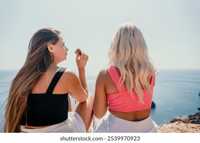 Two Women Enjoying the View and a Snack on a Cliffside - Powered by Shutterstock