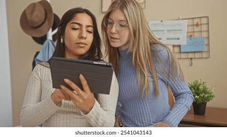 Two women examining a tablet together in a cozy living room setting, reflecting friendship and technology use indoors. - Powered by Shutterstock