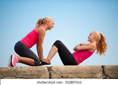 Two Women Exercise On Beach Doing Squats