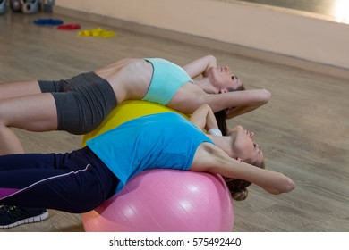 Two Women Exercising On Exercise Ball In Gym