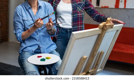 Two Women Female Friends Or Woman With Her Mentor Art Professor Caucasian Mature Sisters Teach And Learn How To Paint Helping During The Painting Ont The Easel At Home In Bright Room Copy Space