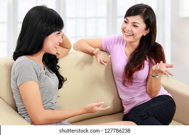 Two Women Friends Chatting On The Couch At Home