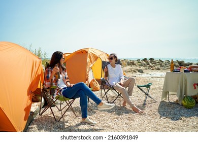 Two women friends drinking cold beer at hot day in camping, joyful girls having fun together during weekend - Powered by Shutterstock