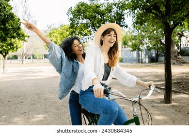 Two women friends enjoying bicycle ride at city park. Young girls having fun during summer vacation. Travel and female friendship concept. - Powered by Shutterstock