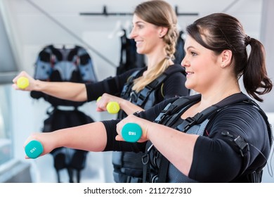 Two women friends exercising together for fitness in ems center