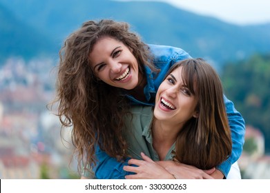 Two Women Friends Laughing And Hugging Outdoors. 