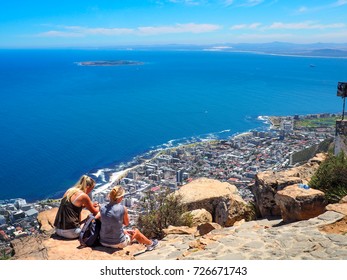 Two Women Friends Sitting And Talk On The Rock On Top Of Lion's Head Mountain With Cityscape And Seascape And Blue Sky Background, Cape Town South Africa At 21 Nov 2016.