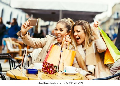 Two Women Friends Taking A Selfie In Cafe After Shopping