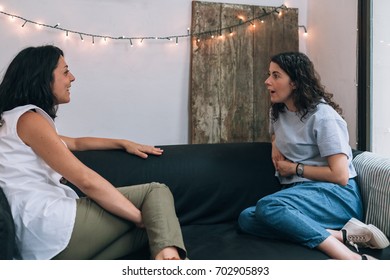 Two Women Friends Talking To Each Other On A Couch In Apartment