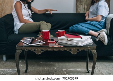 Two Women Friends Talking To Each Other On A Couch In Apartment