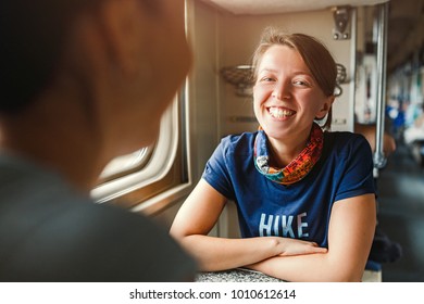 Two women Friends talking and laughing while traveling by econom class train, railroad trip concept