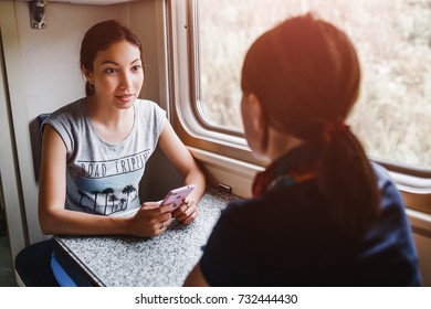 Two women Friends talking and laughing while traveling by reserved ticket train, railroad trip concept