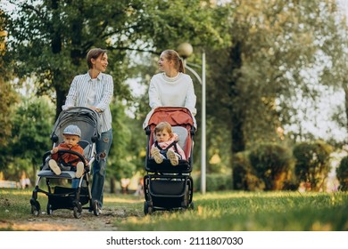 Two women friends walking with baby prams and their kids in park
