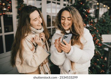 Two women friends walking on festive decorated city street, having fun together. Christmas holiday meetings. - Powered by Shutterstock