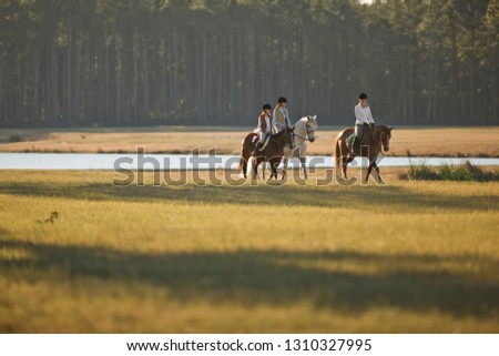 Two women and a girl horseriding in a field