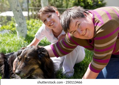 two women and a half breed dog on a field