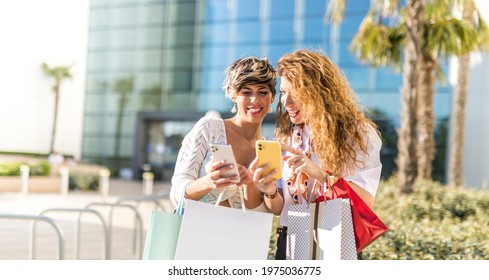 Two women having a good time shopping. Looking in their smart phones