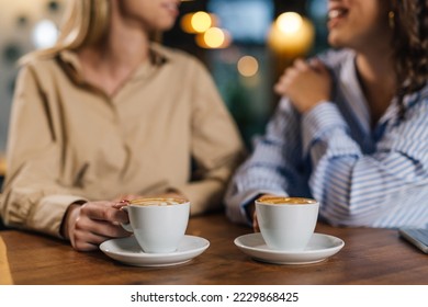 two women holding cups of coffee - Powered by Shutterstock