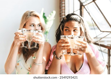 Two women holding multiple glasses, smiling. Casual setting, enjoying drinks. Bright, cheerful atmosphere. Friendship, celebration, fun. Friends drinking Champagne at party. - Powered by Shutterstock