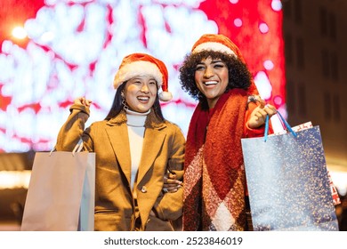 Two women holding shopping bags and smiling during christmas time - Powered by Shutterstock