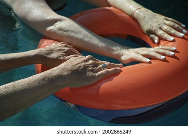 Two Women Holding A Swimming Ring In A Pool, Outdoor Shot With No People