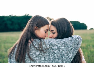 Two Women Are Hugging On The Green  Field.