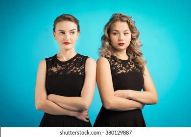 Two women in identical black dresses are angry at each other 