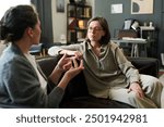 Two women are intently discussing mental health in a counseling session Both are seated on a comfortable couch in a cozy, well-decorated room surrounded by books and personal items