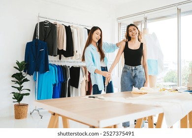 Two women interact in a bright fashion studio, surrounded by colorful clothing, showcasing creativity and style. - Powered by Shutterstock