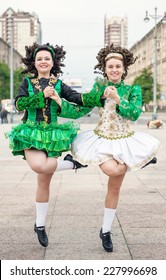Two women in irish dance dresses and wig dancing 