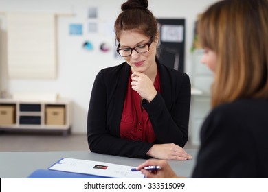 two women in a job interview sitting at the desk looking at a curriculum vitae - Shutterstock ID 333515099