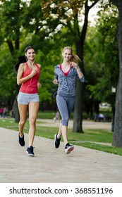 Two Women Jogging In Park And Listening To Music