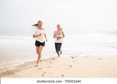 two women is jogging the seashore on an overcast day - Powered by Shutterstock