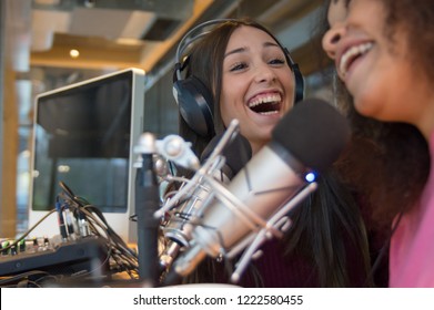 Two Women Laughing And Having Fun Singing Togheter On Microphone In A Radio Studio