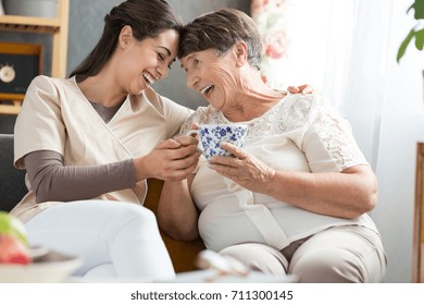 Two Women Laughing Together At A Funny Joke During Afternoon Tea Break In Retirement Home