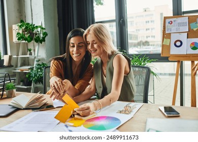 Two women, lesbian couple, collaborate on a project in a modern agency workspace, discussing color palettes and designs. - Powered by Shutterstock