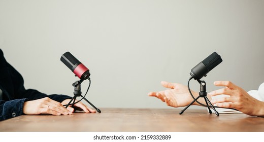 Two women in local broadcat studio recording audio podcast. Sitting opposite each other, hands close-up - Shutterstock ID 2159332889